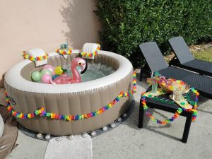 Spa gonflable décoré avec guirlande tropicale, ballons et flamant rose gonflable.