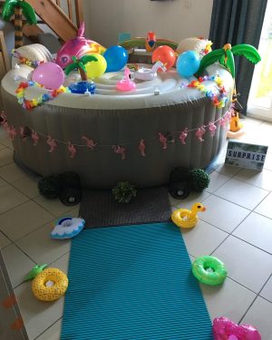 Spa gonflable décoré en intérieur avec ballons, bouées tropicales et palmiers gonflables.