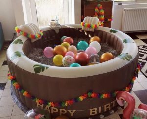 Spa gonflable décoré avec ballons colorés, guirlande tropicale et flamant rose.