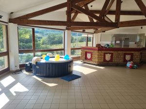 Spa gonflable décoré avec ballons dans une grande salle lumineuse aux poutres en bois.