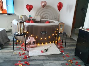 Spa Dans Ma Bulle décoré avec pétales rouges, ballons cœur et lanternes dorées.