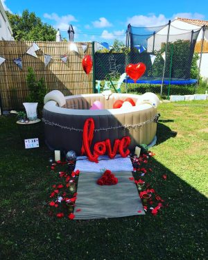 Spa Dans Ma Bulle installé dans un jardin avec ballons, pétales et décorations romantiques.