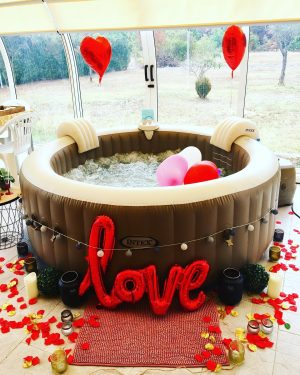 Spa décoré avec ballons rouges en forme de cœur, guirlande lumineuse et grand ballon "LOVE".