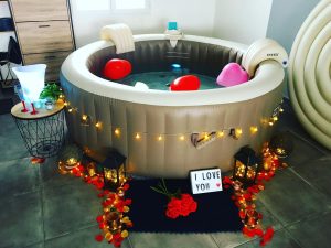 Spa gonflable décoré pour une soirée romantique avec pétales de roses, guirlandes lumineuses et lanternes.