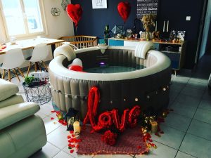 Spa gonflable décoré de pétales, ballons cœur et guirlandes lumineuses