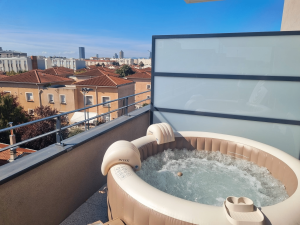 Spa gonflable installé sur une terrasse avec vue dégagée sur les toits d’une ville, sous un ciel bleu.