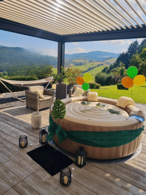Spa gonflable décoré en thème tropical sous pergola avec vue sur les montagnes.