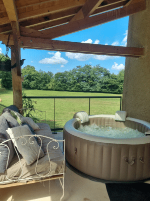 Spa gonflable installé sous un auvent en bois avec vue sur un grand espace vert.