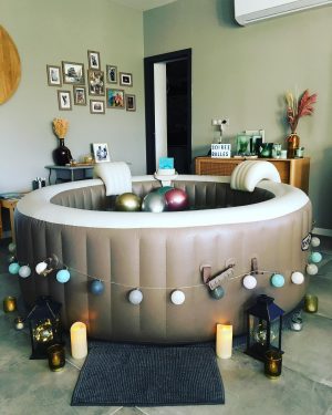 Spa gonflable décoré en intérieur avec guirlande pastel, lanternes et ballons.