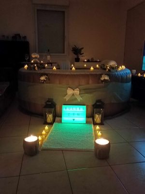 Spa décoré avec bougies LED et guirlandes lumineuses dans une pièce sombre.