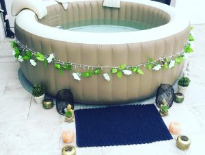 Spa décoré avec guirlande de fleurs blanches, bougies et statues zen.